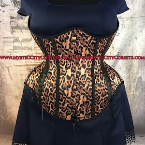 May include: A black and brown leopard print corset with black boning and black lacing in the back. The corset is made of satin and has a smooth, shiny finish. www.mysticcitycorsets.com