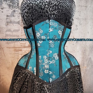 May include: A turquoise blue corset with black boning and a floral pattern. The corset has a satin finish and is made of high-quality materials. www.mysticcitycorsets.com