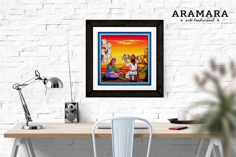 May include: A framed artwork depicting a colorful scene of two people sitting on a beach at sunset. The artwork is in a black frame and has the text "ARAMARA arte tradicional" in the top right corner.