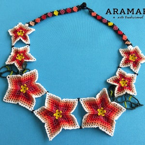 May include: A beaded necklace with a floral design. The necklace is made of white, red, orange, yellow, and green beads. The necklace is called "Aramara arte tradicional".