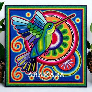 May include: A colourful, hand-painted artwork depicting a hummingbird in flight. The hummingbird is surrounded by concentric circles of vibrant colours, including red, orange, yellow, green, blue, and purple. The artwork is signed "ARAMARA arte tradicional" in the bottom centre.