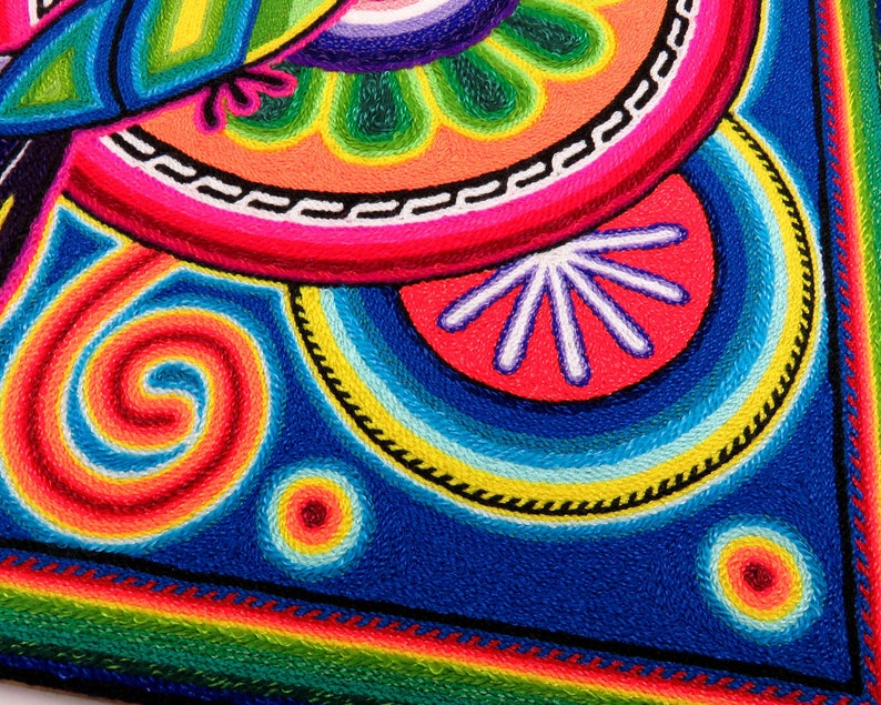 May include: A colourful embroidered artwork featuring a spiral design, a flower, and a bird. The artwork is made with vibrant colours, including red, orange, yellow, green, blue, and purple.