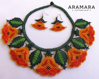 May include: A beaded necklace and earrings set featuring orange and red flowers with green leaves. The necklace is black and the earrings are silver. The set is labeled "ARAMARA arte tradicional".