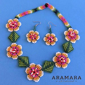 May include: A beaded necklace and earrings set with a floral design. The necklace features white, orange, pink, and green beads, while the earrings are white, orange, and pink. The set is labeled "ARAMARA arte tradicional".