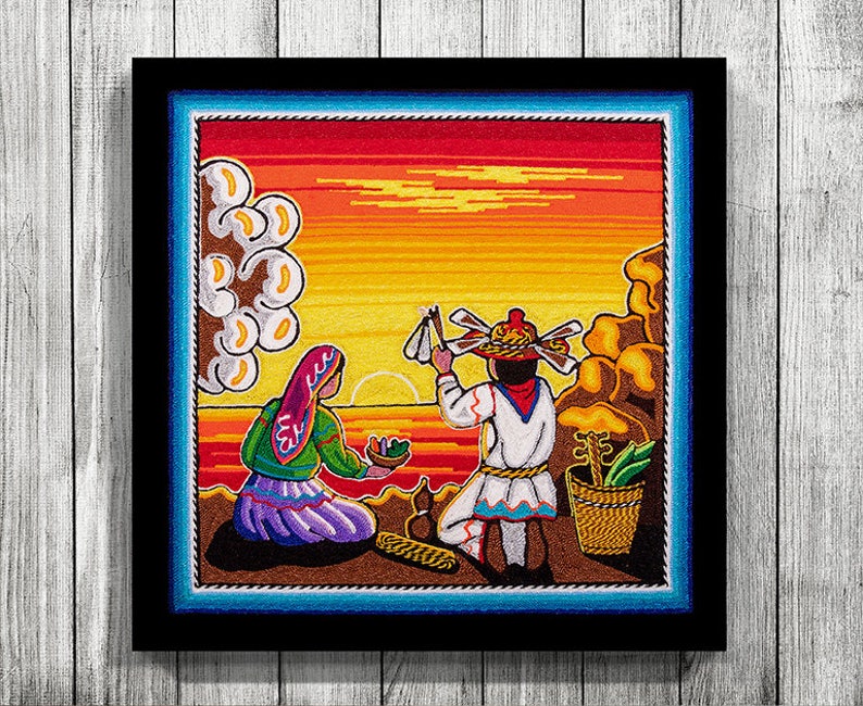 May include: A colorful embroidered artwork depicting two figures in traditional clothing against a sunset backdrop. The woman wears a purple dress and a red headscarf, while the man holds a stick with feathers. The scene is framed by a blue and brown border.