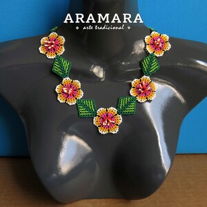 May include: A beaded necklace with a floral design. The necklace is made with white, pink, yellow, and green beads. The necklace is on a gray mannequin.
