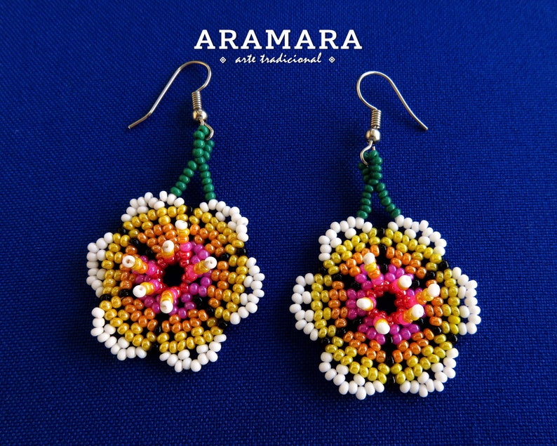 May include: A pair of beaded flower earrings with a green and silver hook. The flowers are made with white, yellow, orange, pink, and black beads.