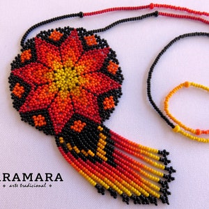 May include: A beaded necklace with a large, round pendant featuring a red, orange, and yellow flower design. The pendant is attached to a black beaded chain with a fringe of beads in the same colors.