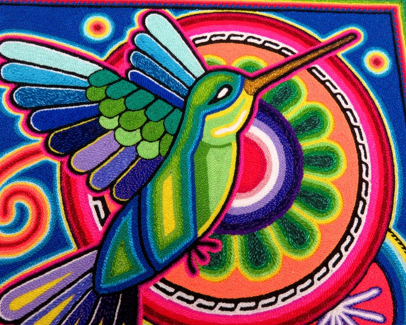 May include: A colourful embroidered artwork featuring a hummingbird with outstretched wings, flying over a circular design with concentric rings and a flower-like pattern.