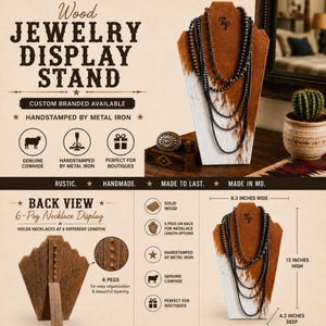 May include: A wood jewellery display stand covered in white and brown cowhide, featuring a multi-strand beaded necklace. The stand measures 13 inches high, 8.3 inches wide, and 4.3 inches deep, with six pegs on the back for necklace organisation.