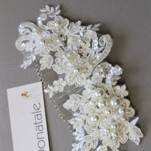 May include: Two white lace hair combs with pearl and sequin detailing. The combs have floral patterns and are attached to a tag that reads "Donatale". The combs are on a grey surface.