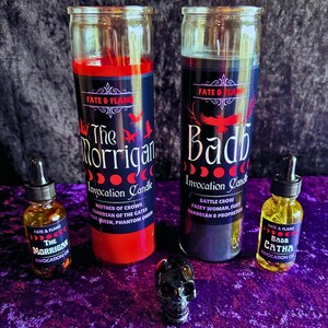 Peut inclure: Deux pots de bougies en verre avec de la cire rouge et noire, étiquetés "The Morrigan Invocation Candle" et "Badb Invocation Candle". Les bougies sont à côté de deux petites bouteilles d'huile en verre étiquetées "The Morrigan Invocation Oil" et "Badb Catha Invocation Oil". Un crâne noir se trouve devant les bougies.