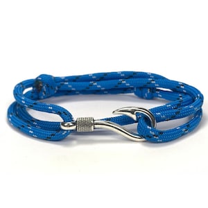 May include: A blue rope bracelet with a silver-colored hook clasp. The rope is a vibrant blue with a pattern of white and black flecks. The bracelet is designed to wrap around the wrist.