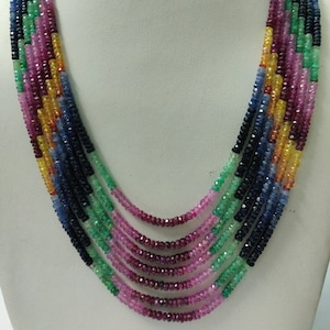Puede incluir: Collar multicadena hecho con cuentas de piedras preciosas azules, verdes, rosas y amarillas. El collar está en capas y presenta una variedad de colores y formas.
