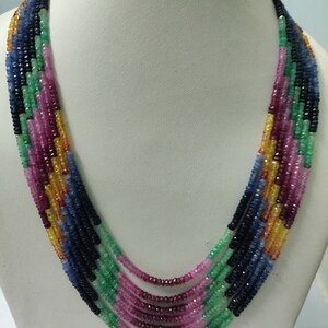 Può includere: Collana multifilo realizzata con perline di pietre preziose blu, verdi, rosse e gialle. La collana è a strati e presenta una varietà di colori di pietre preziose.
