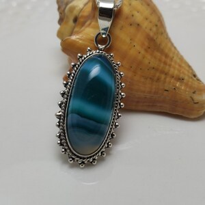 May include: A silver pendant with a blue and white agate stone set in a decorative silver frame.