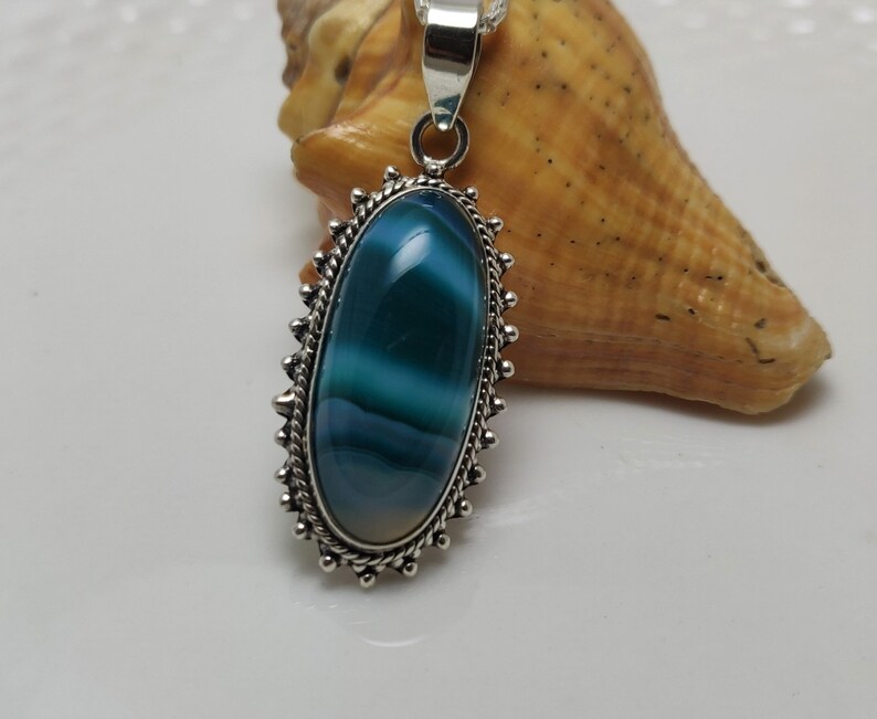 May include: A silver pendant with a blue and white agate stone set in a decorative silver frame.