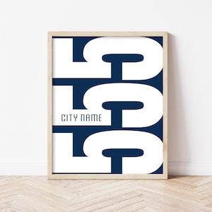 May include: A framed rectangular wall art print featuring a dark navy blue background with three large, stacked white letter G characters. The text CITY NAME is printed in a smaller, clean, sans-serif font on the left side of the middle letter.