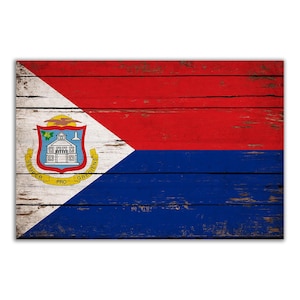 May include: A distressed wooden sign with the flag of Sint Maarten. The flag is red, white, and blue with a coat of arms in the upper left corner. The coat of arms features a building with a yellow roof and a green tree. The text "SEMPER PRO GREDIENS" is written around the coat of arms.