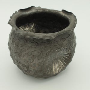 May include: A set of three ceramic mugs with a speckled, matte finish. The mugs are in shades of cream, light gray, and dark gray. Each mug has a simple, minimalist design and a rounded handle.