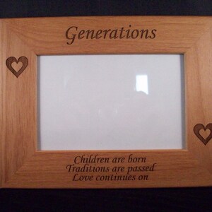 May include: A wooden picture frame with a light brown finish. The frame has a cutout heart design on each side and the text "Generations" engraved at the top. The text "Children are born Traditions are passed Love continues on" is engraved at the bottom.
