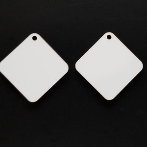 May include: Two white diamond-shaped sublimation blanks with a hole at the top for hanging.