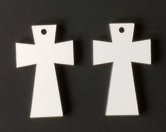 May include: Two white wooden cross shapes with a hole at the top for hanging. The crosses are about 3 inches tall.