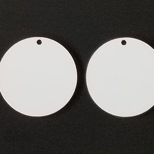 May include: Two white round blank ornaments with a hole at the top for hanging.
