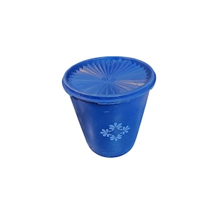 May include: A blue plastic container with a matching lid. The lid has a ridged design, and the container features a floral pattern. The container is cylindrical and appears to be a storage item.