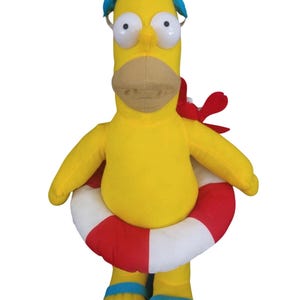May include: A plush yellow character wearing blue swim goggles, a red and white life preserver, and blue sandals. The character has large white eyes, a tan beak, and a red crab attached to its shoulder.