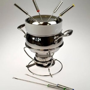 May include: A stainless steel fondue set with a white ceramic insert and six color-coded forks. The set includes a stand and a burner, perfect for a cozy gathering. The forks have red, yellow, and green tips.