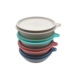 May include: Stack of four colorful food storage bowls with lids. The bowls are in shades of gray, teal, pink, and blue. Each bowl has a matching lid and a handle for easy carrying. The lids are light gray.