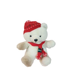 May include: A white teddy bear wearing a red knit hat with white star patterns and a red scarf with green and white accents. The bear has a black nose and is set against a white background.