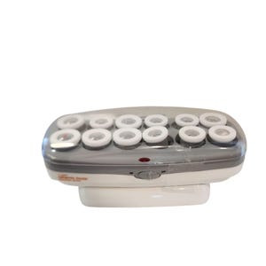 May include: A white and gray electric hair setter with a clear plastic lid, featuring twelve cylindrical heating posts with white circular tops. The base includes an on-off switch, a small red indicator light, and the text ceramic tools.