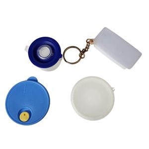 May include: A collection of Tupperware lids and containers in blue and white. Includes a blue lid with a yellow button, a white lid, a blue and white container with a keychain, and a white rectangular container attached to the keychain.