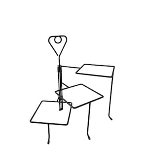 May include: A black metal tiered display stand featuring three square platforms arranged at different heights. The structure is supported by a central vertical rod topped with a heart-shaped handle containing a circular loop at the very peak.