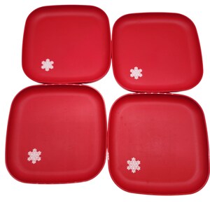 May include: Four red square plates with rounded corners, each featuring a white snowflake design in the lower center. The plates are arranged in a square formation, perfect for holiday or winter-themed dining.