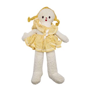 May include: A soft, plush doll with a cream-colored body and long legs. The doll has a yellow gingham dress with a ruffled collar and a matching bonnet with braided pigtails. The doll's face features embroidered eyes and a red mouth.