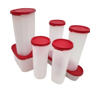 May include: A collection of white plastic food storage containers with red lids. The containers are various sizes and shapes, including tall, rectangular, and oval designs. The lids fit snugly on top.
