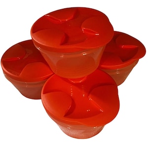 May include: Four clear plastic food storage containers with bright orange lids. The lids have a unique design with curved indentations. The containers are stacked, showcasing their shape and color.