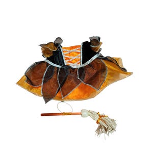 May include: A Halloween costume set featuring an orange, black, and brown dress with silver trim and a matching toy broom. The dress has a corset-style bodice and layered skirt. The broom has a wooden handle and straw bristles.