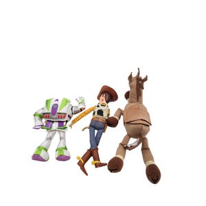 May include: Three plush toys from the Toy Story franchise. Buzz Lightyear in a white and green spacesuit, Woody in a cowboy outfit, and a brown horse. The toys are set against a white background.