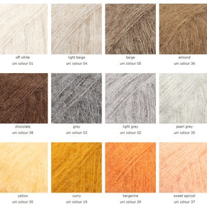 May include: A color chart of yarn samples in various shades of white, beige, brown, grey, yellow, and orange. The yarn is a soft, fuzzy mohair blend. Each sample is labeled with the color name and a corresponding uni color number.