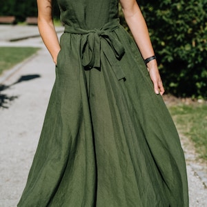K&ouml;nnte beinhalten: Ein langes, flie&szlig;endes gr&uuml;nes Leinenkleid mit einer Schleife in der Taille. Das Kleid hat ein schlichtes, elegantes Design und ist perfekt f&uuml;r einen Sommertag.