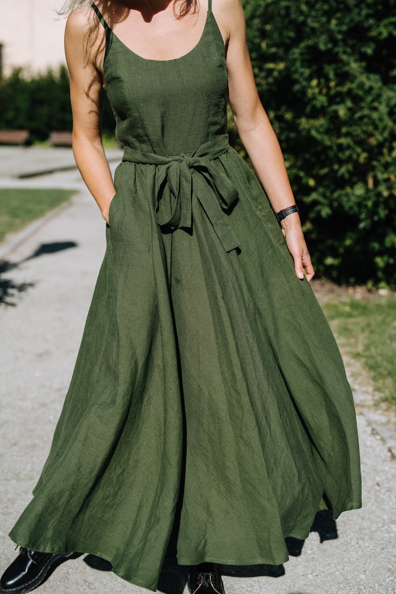 K&ouml;nnte beinhalten: Ein langes, flie&szlig;endes gr&uuml;nes Leinenkleid mit einer Schleife in der Taille. Das Kleid hat ein schlichtes, elegantes Design und ist perfekt f&uuml;r einen Sommertag.