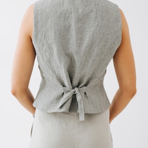 May include: A gray linen vest with thin black stripes. The vest has a tie closure in the back.