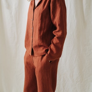 Puede incluir: Un conjunto de camisa y pantal&oacute;n de lino de color &oacute;xido. La camisa tiene cuello y mangas largas. El pantal&oacute;n tiene pierna recta.