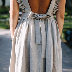 May include: A light gray linen dress with a low back and a bow tie at the back.