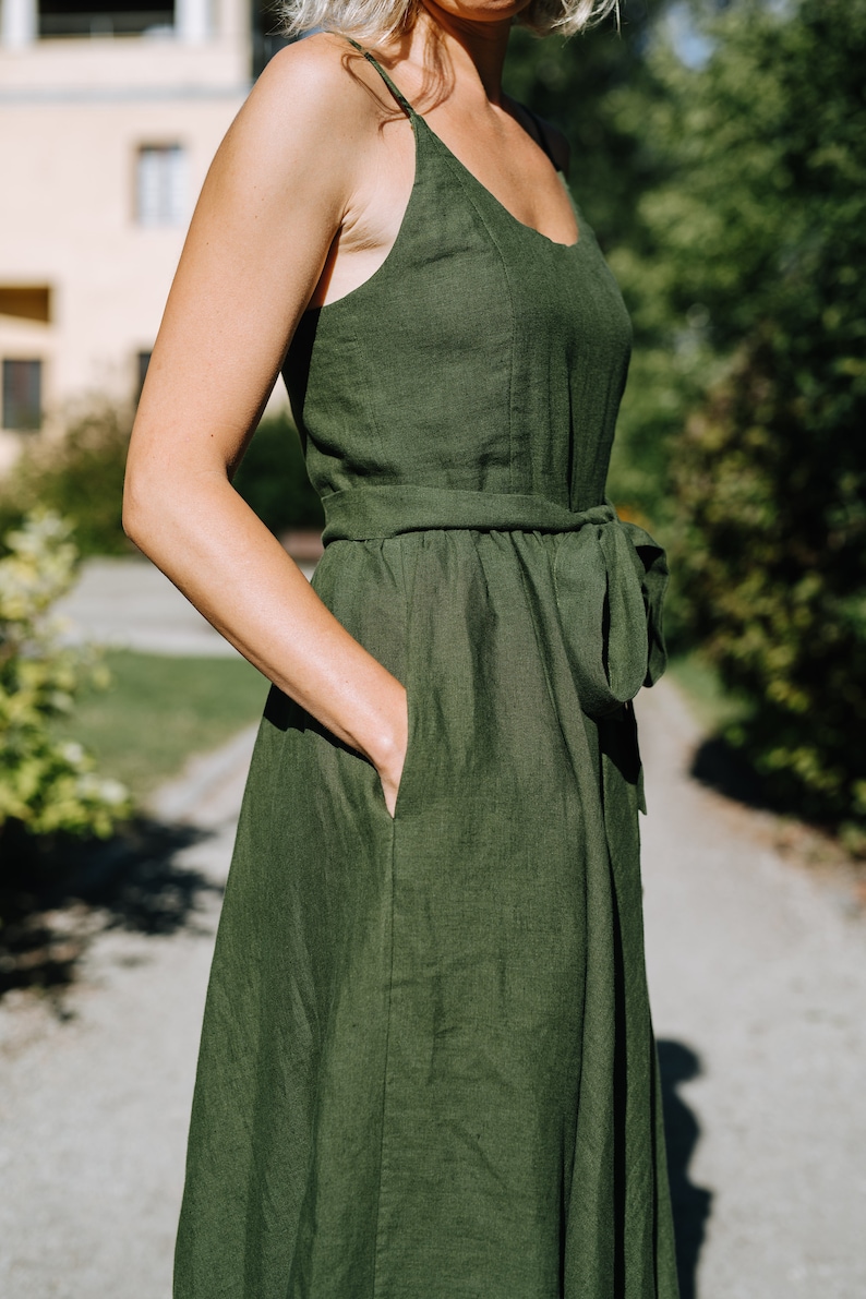 K&ouml;nnte beinhalten: Ein dunkelgr&uuml;nes Leinenkleid mit Bindeg&uuml;rtel und Taschen. Das Kleid ist &auml;rmellos und hat einen runden Ausschnitt.