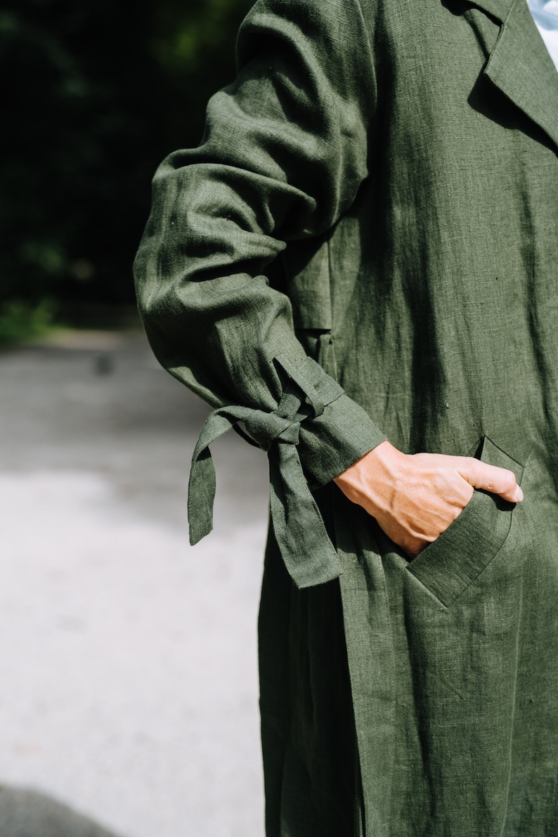May include: A dark green linen jacket with a tie detail on the sleeves and a pocket on the front.